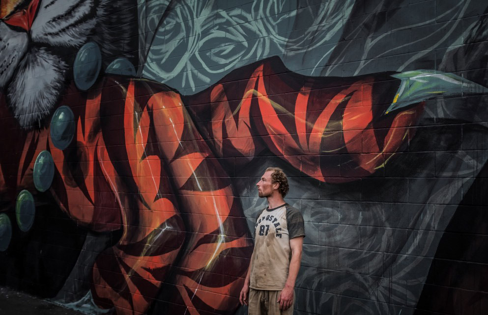 An image of a man standing in front of a mural
