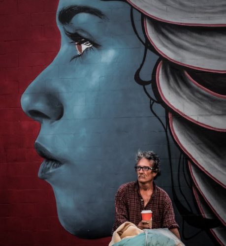 An image of a man sitting in front a muraled wall