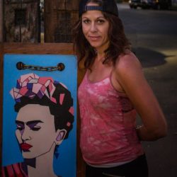 An image of a woman next to a paining of Frida Kalo